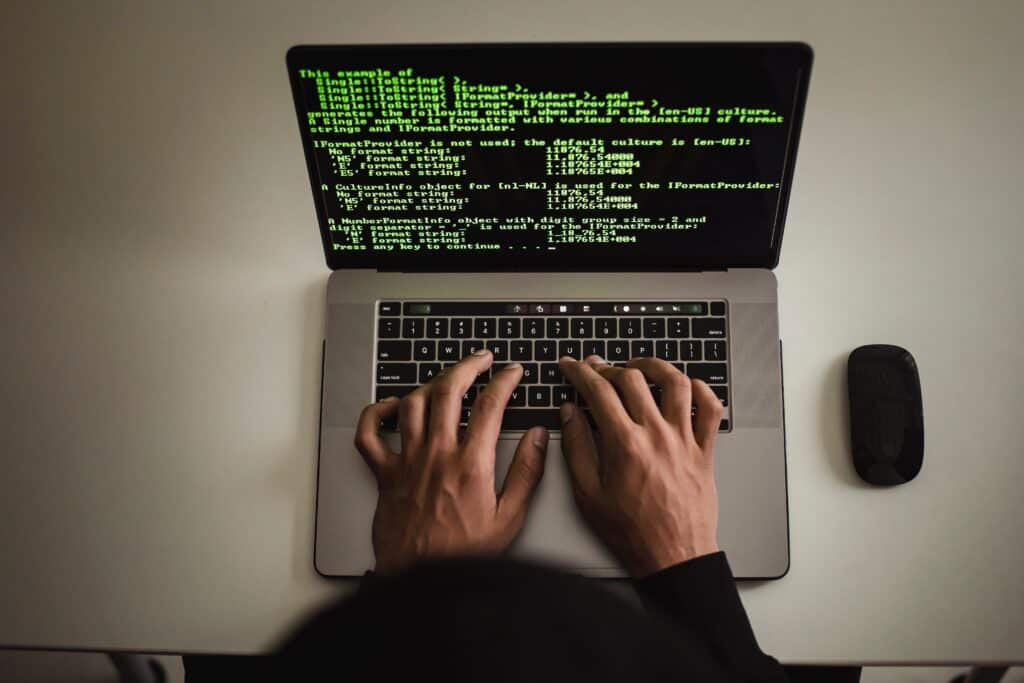 Person typing on a laptop with code on the screen.